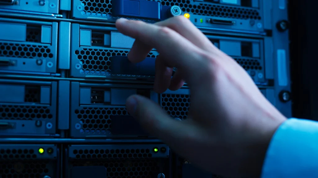 Eine Hand greift nach einem blauen Gerät in einem Serverraum